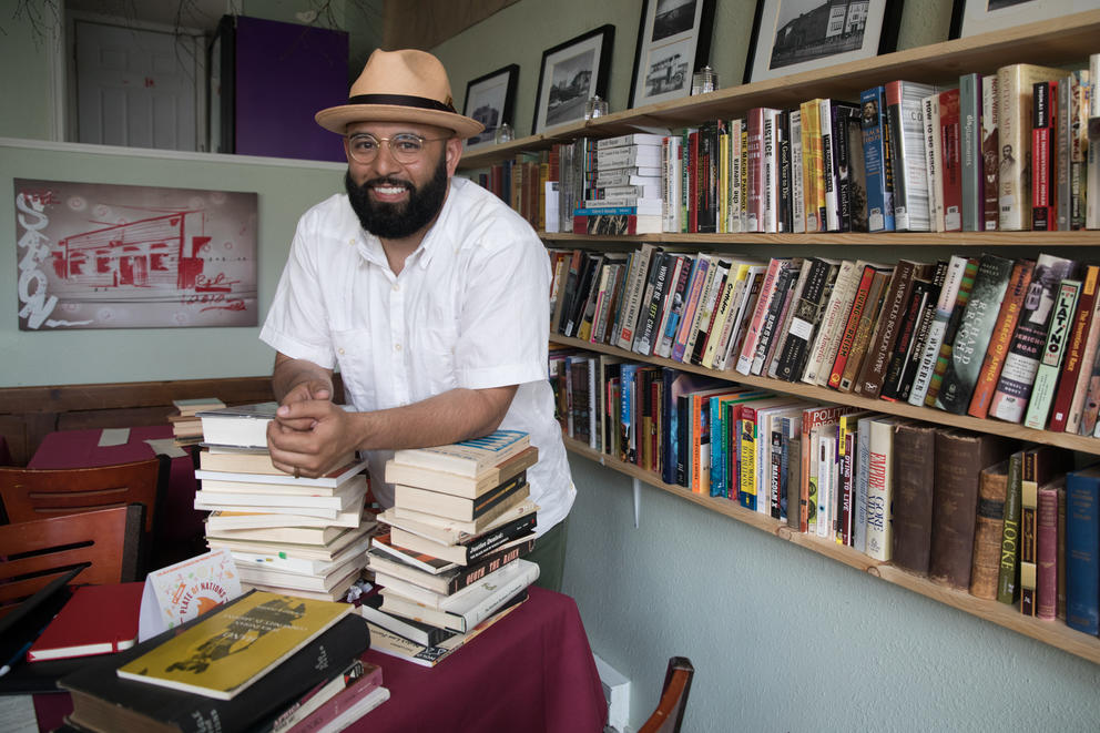 Estelitas Library founder, community organizer and activist Edwin Lindo stands amid an array of books.