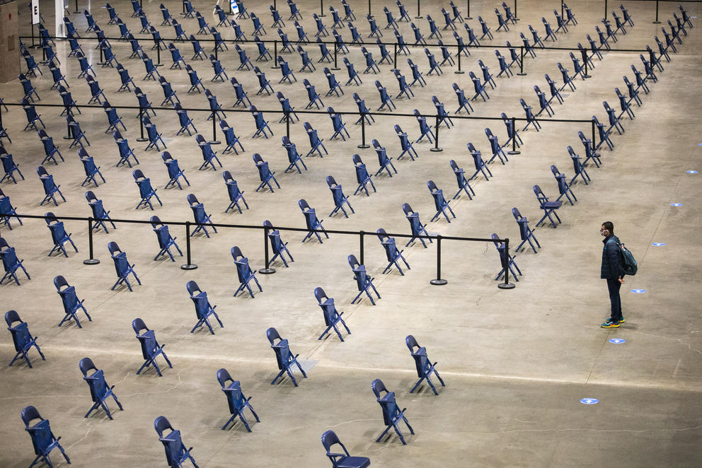 a figure stands alone in front of rows and rows of empty folding chairs inside Lumen Field Event Center