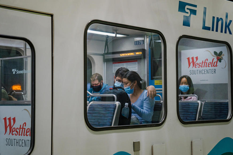 Masked riders are seen through the windows of the Light Link Rail train
