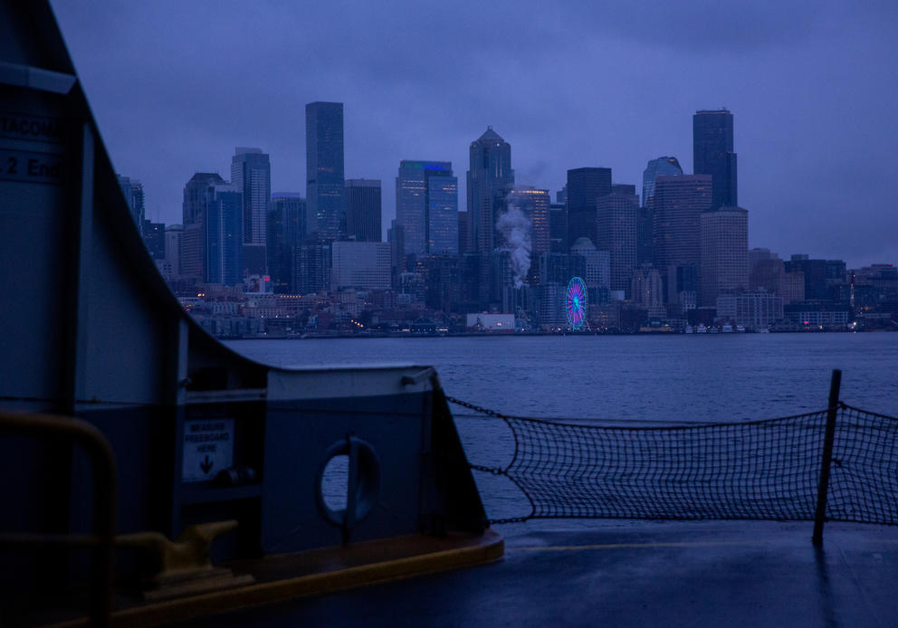 The Seattle skyline is seen above the edge of a ferry boat during the blue hour