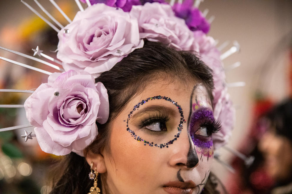 A close up of a young woman with face paint and a flower crown