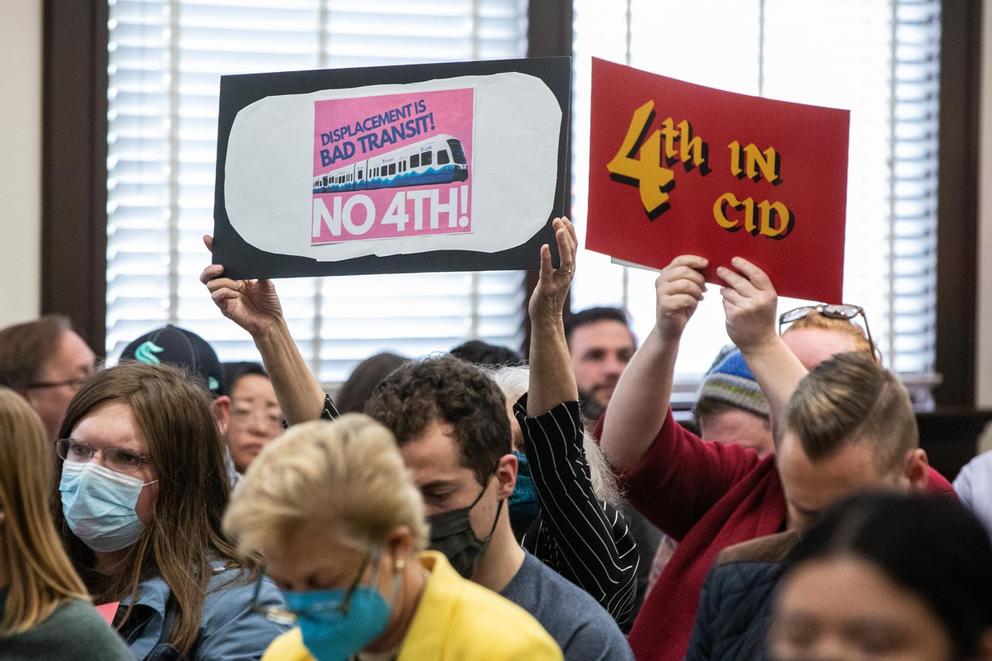 people hold signs in a crowded board room