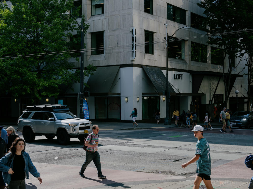 Pedestrians and vehicles pass below a traffic camera in downtown Seattle