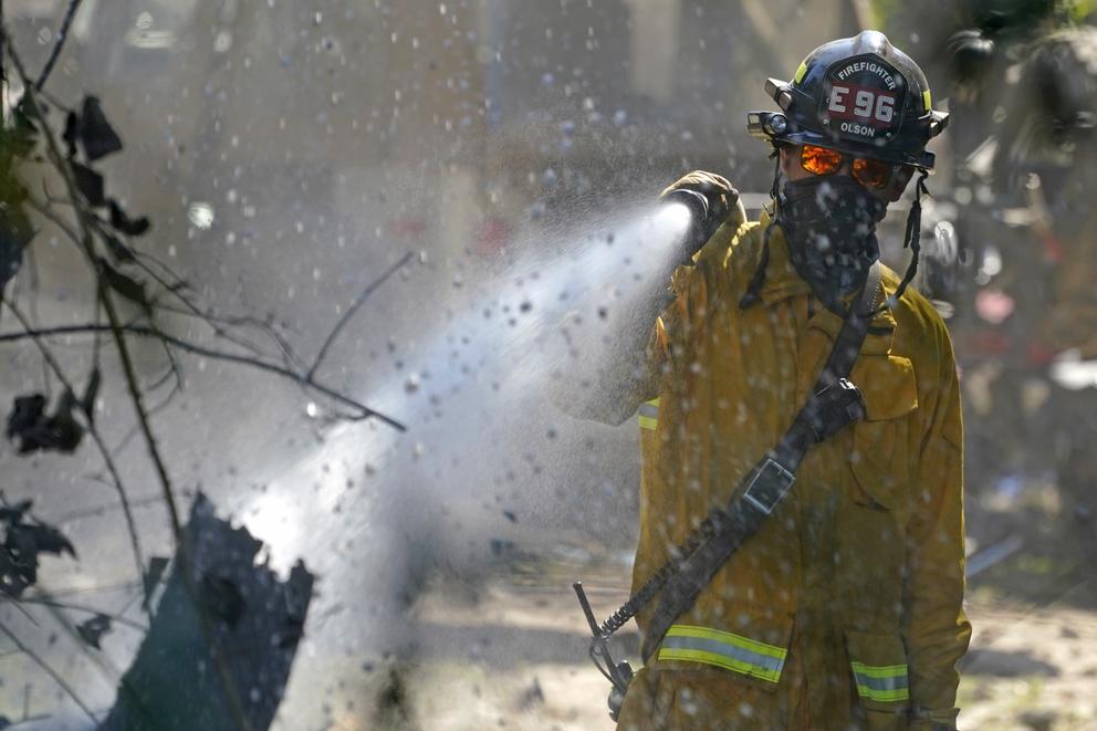 a firefighter sprays a tree with a hose