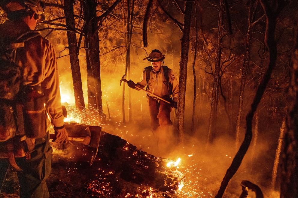 a wildland firefighter stands in the middle of a wildfire