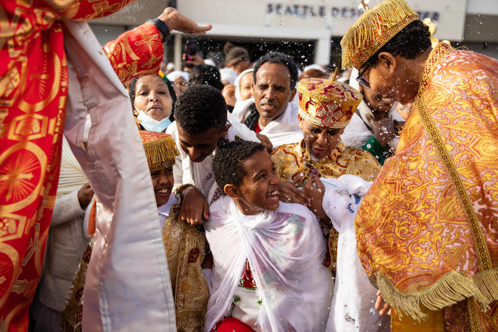 Congregants in traditional dress are sprinkled with holy water