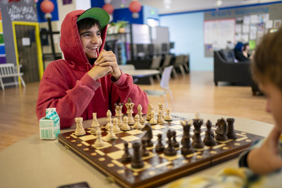 A boy smiles while playing chess
