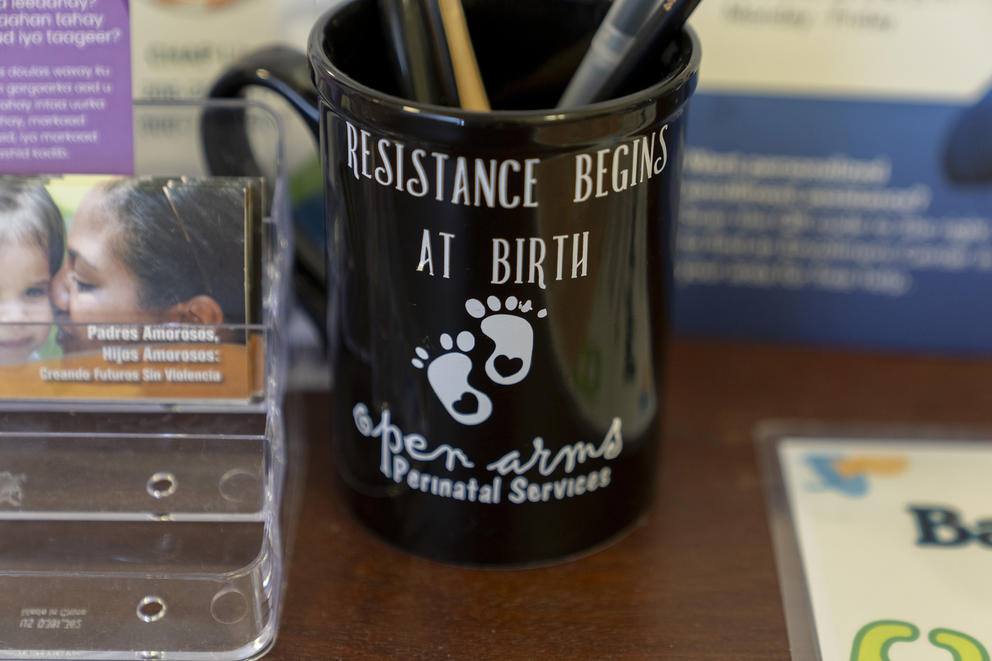 A mug with the words "resistance begins at birth" sits on a table.