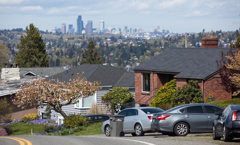 The Seattle skyline in the distance as seen from the south, behind a neighborhood on a hill.