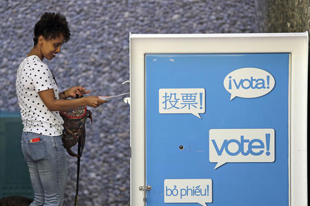A woman puts her ballot into a ballot box