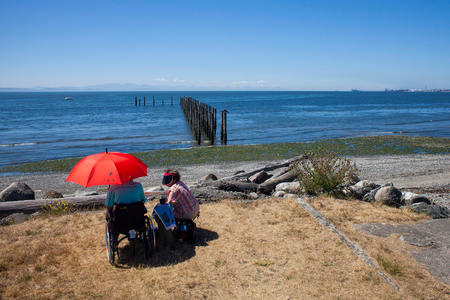 Two people sit on a beach in Point Roberts, Washington