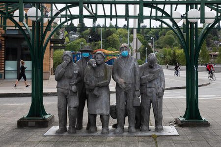 Statues under a bus shelter wearing masks. A public sculpture in Seattle's Fremont neighborhood