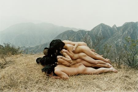 a photograph of five naked people piled on top of each other on a mountain top