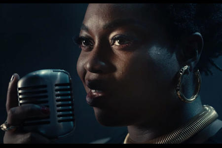 close photo of a Black woman singing at a microphone