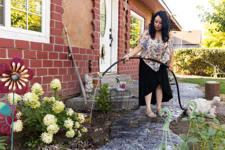 Silvia Zarate waters plants in the front yard of her home