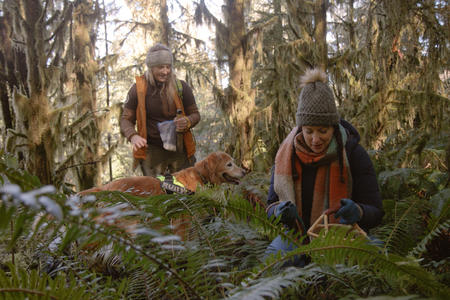 Host Rachel Belle digs up truffles in a mossy forest while her guest Alana McGee guides her along with her golden retriever, Ruby