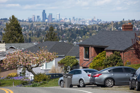 The Seattle skyline in the distance as seen from the south, behind a neighborhood on a hill.