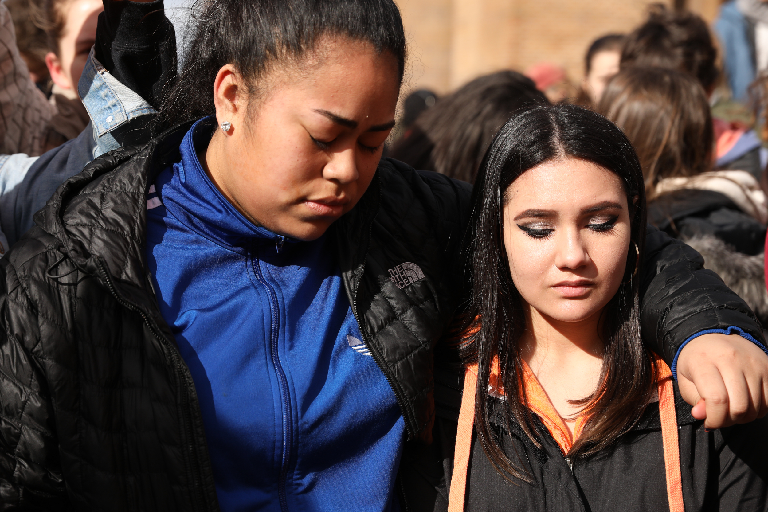 (From left) Nathan Hale High School seniors Precious Anetipa and Melanie Remmers embrace each other during a moment of silence in honor of Parkland High School shooting victims at University of Washington's Red Square, Mar. 14, 2018. (Photo by Matt M. McKnight/Crosscut)