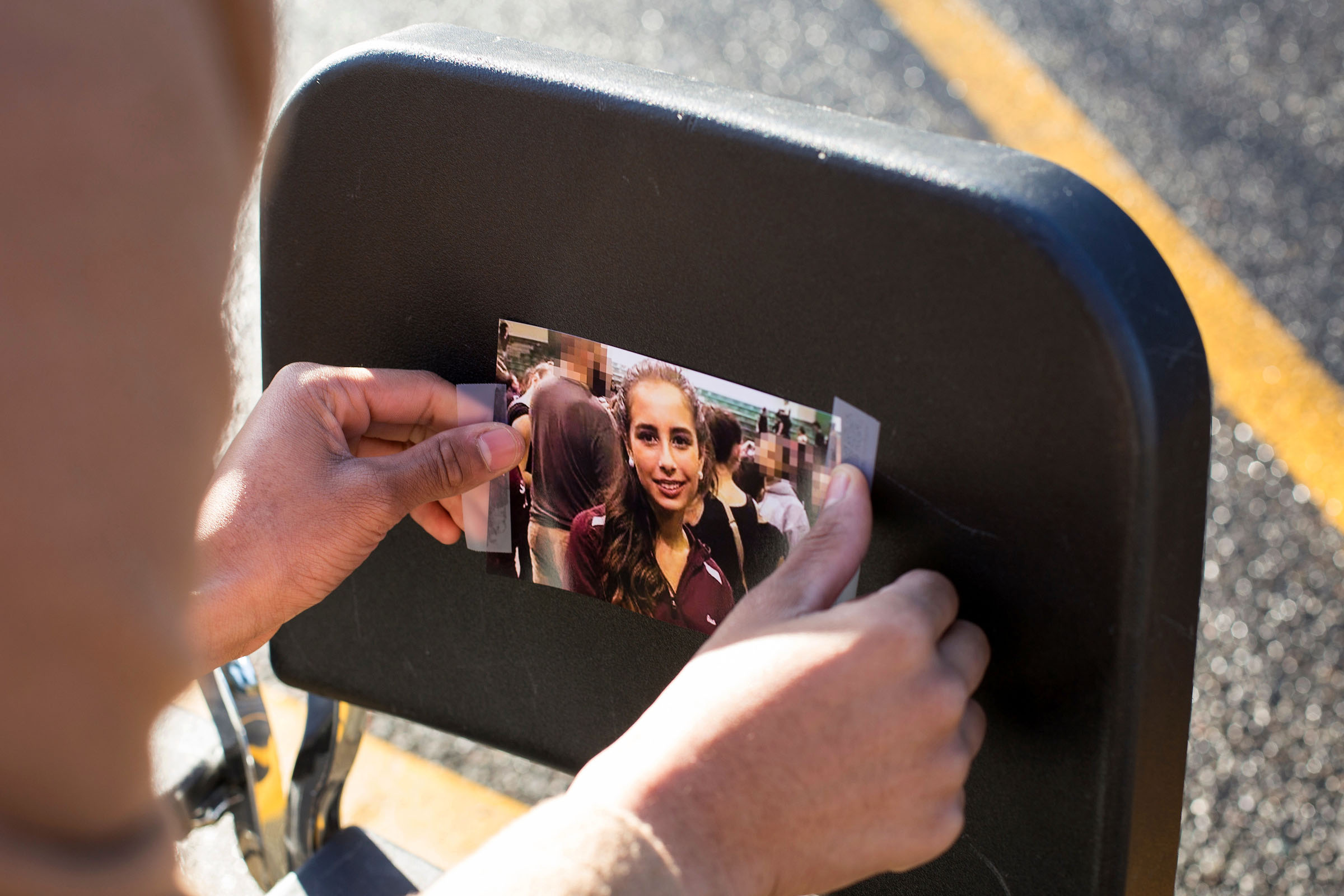 A Tumwater High School student tapes a photo of a victim of the high school shooting in Parkland, Florida in February. (Photo by David Ryder for Crosscut)