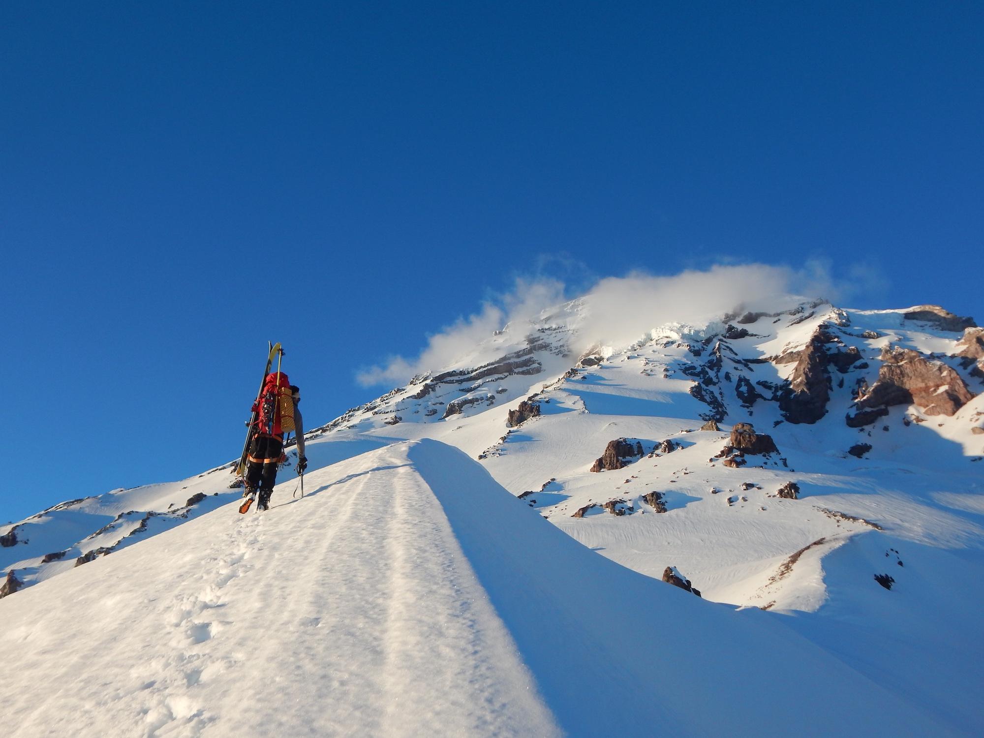 Conrad Wharton heads up slope at Mount Rainier National Park to make a ski run