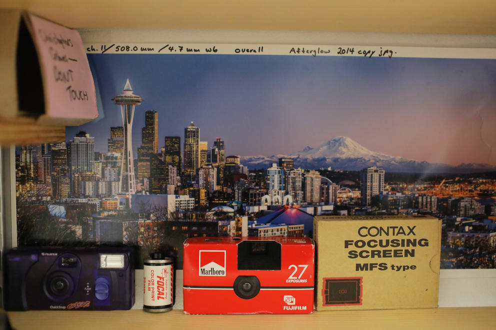 Old film rolls, cameras, and a photo of the Seattle skyline sit on a shelf