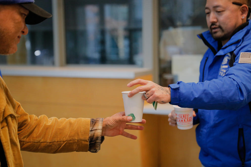 A CARE team member hands a cup of tea to another man