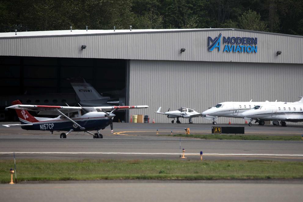 There are several airplanes outside of a hangar.