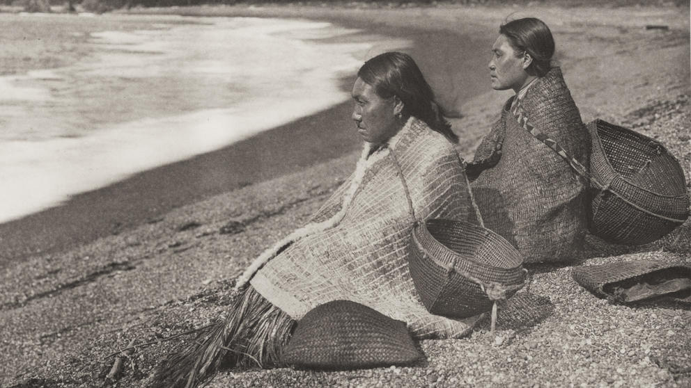Two Native American on a beach with baskets for clams. 