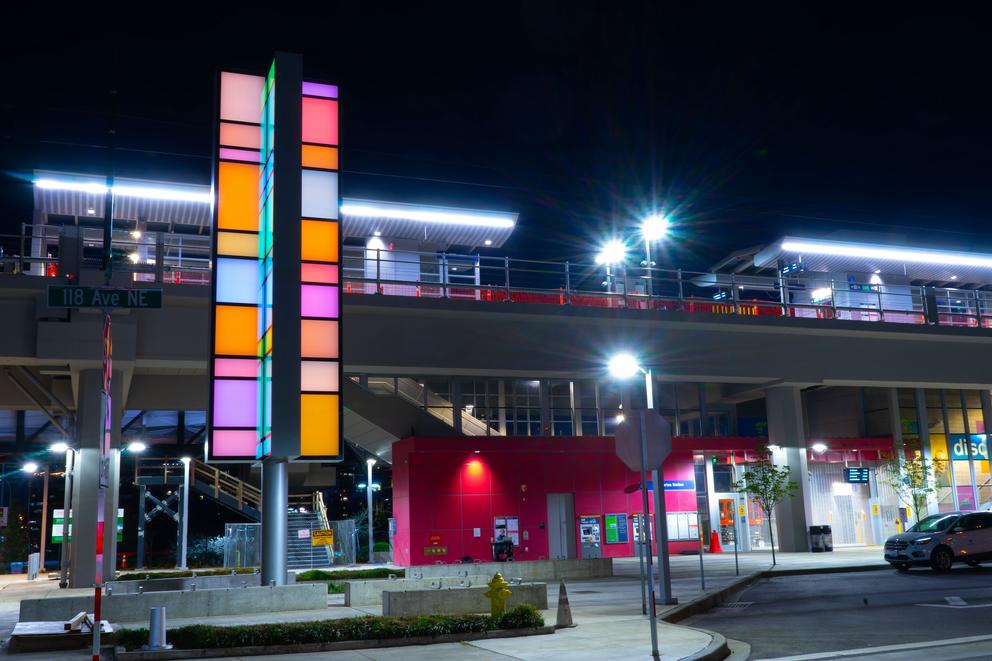 photo of an elevated train at night, with a colorful column of light in front