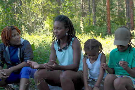 Two women sitting with two children in the forest