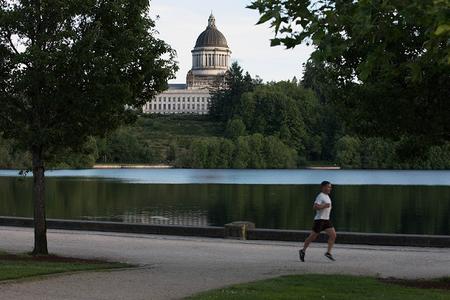 A jogger runs along Capitol Lake with the state Legislative Building in the background