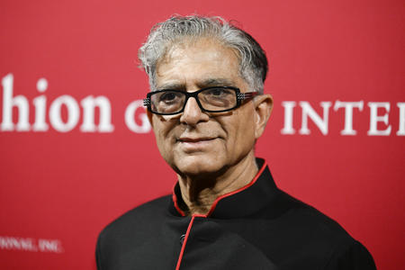 Portrait of a man with glasses and gray hair against a red backdrop