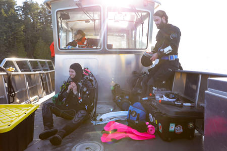 Divers on the deck of a boat put on equipment 